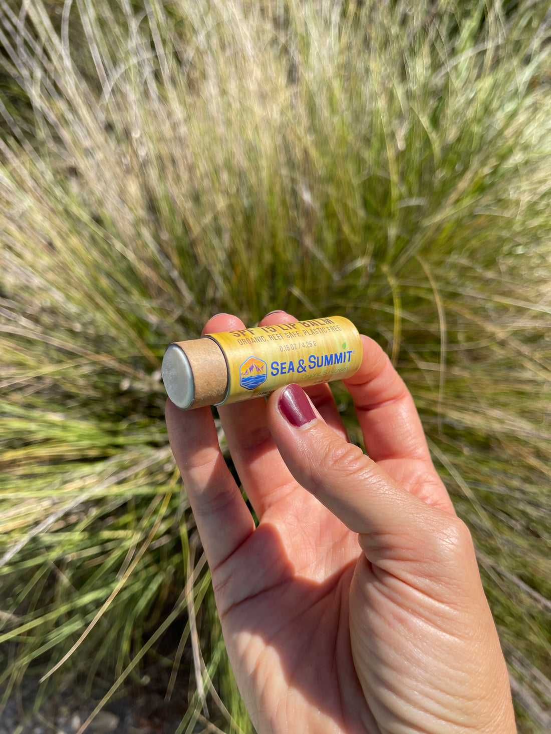 SFP 15 organic sunscreen lip balm held up outside in recyclable packaging.
