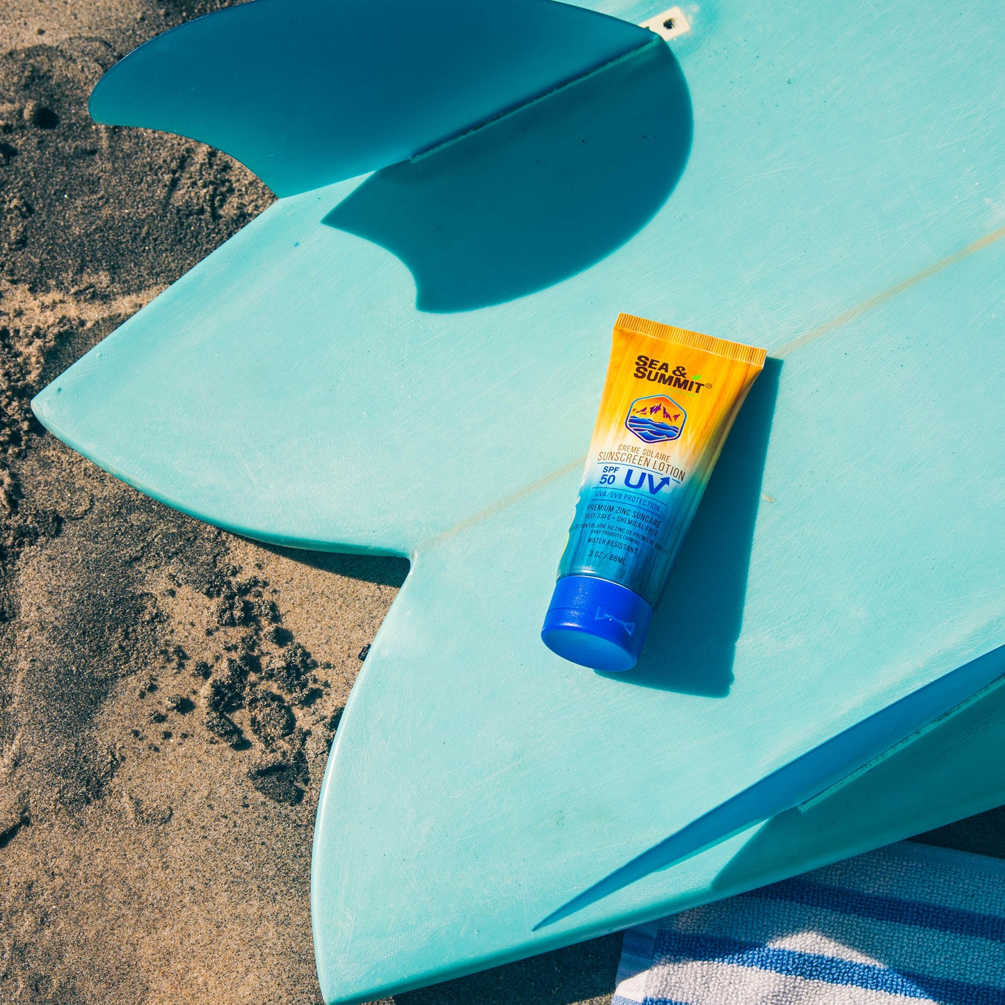 SPF 50 natural lotion in a recycled plastic tube, lies on a surfboard at the beach