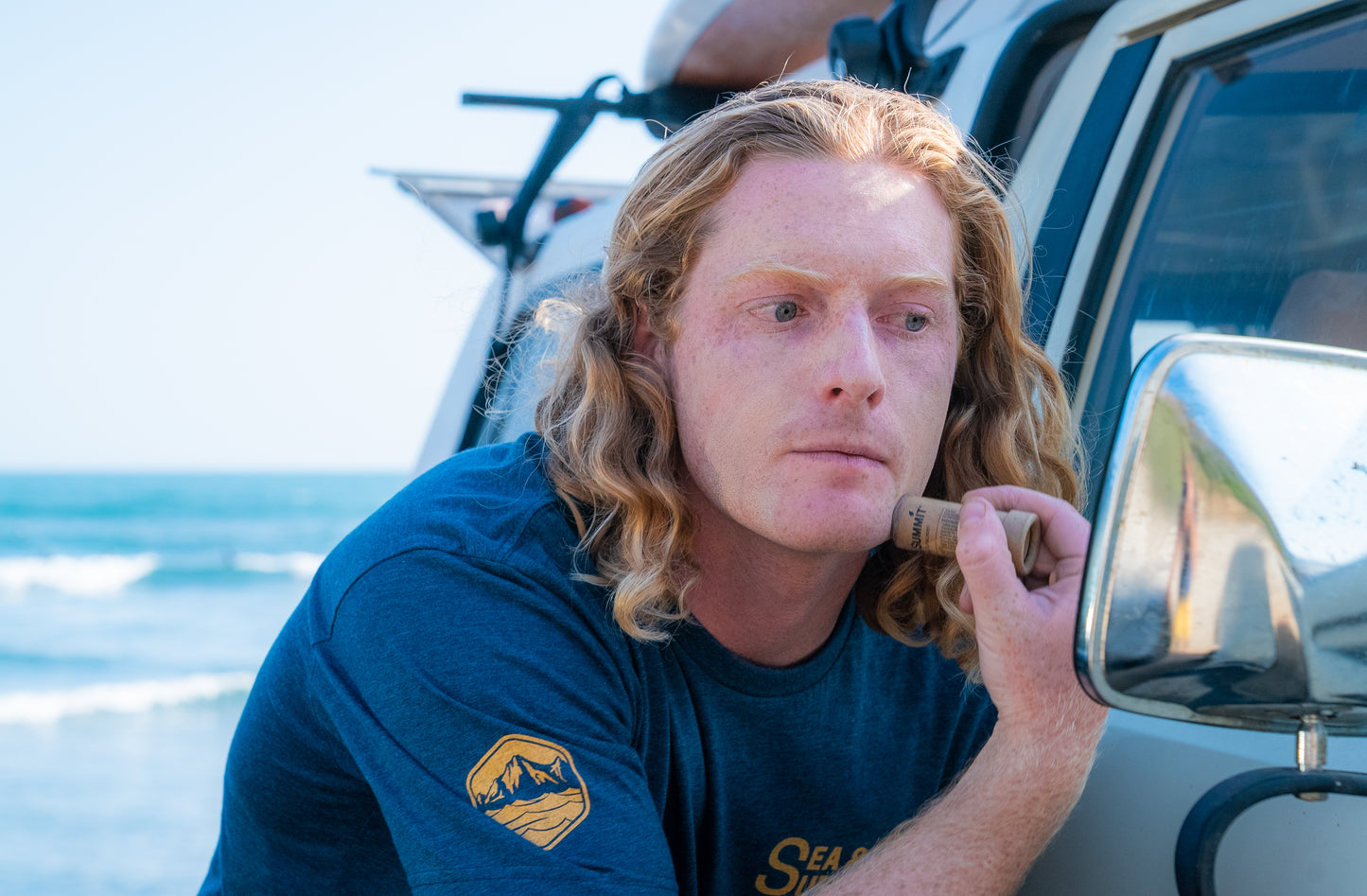 Pre-surf sunscreen routine. Justin applies the SPF 50 face stick using his car mirror before hitting the waves.