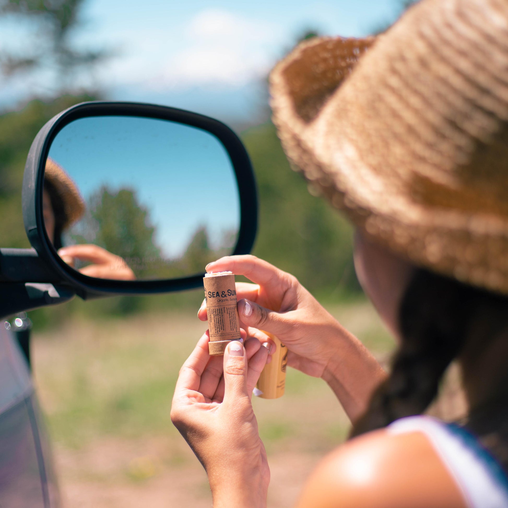Summer scenes, Kat applies the SPF 36 organic face stick using the wing mirror of her van.